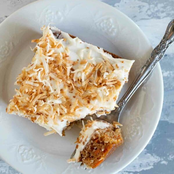 overhead view of slice of carrot sheet cake on a plate with a fork