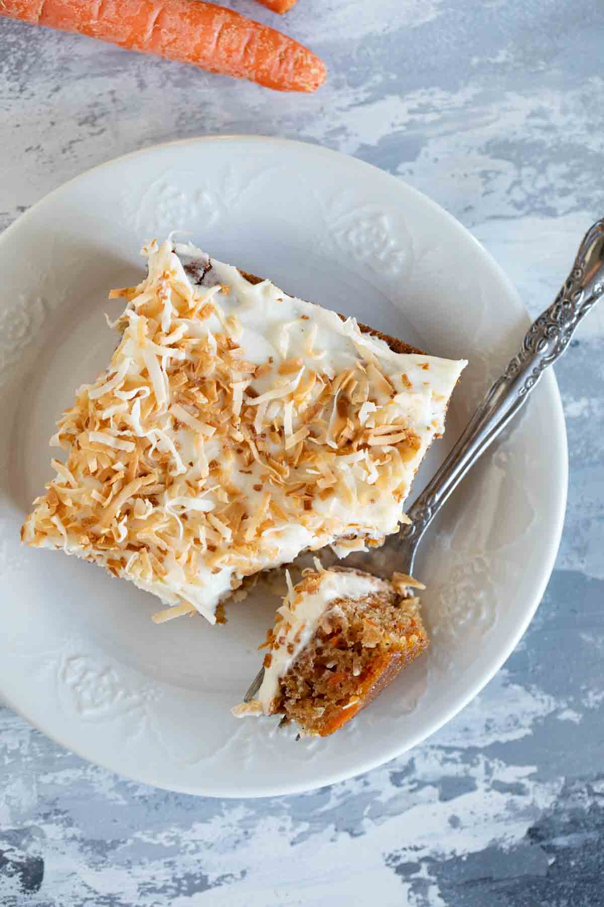 overhead view of slice of carrot sheet cake on a plate with a fork