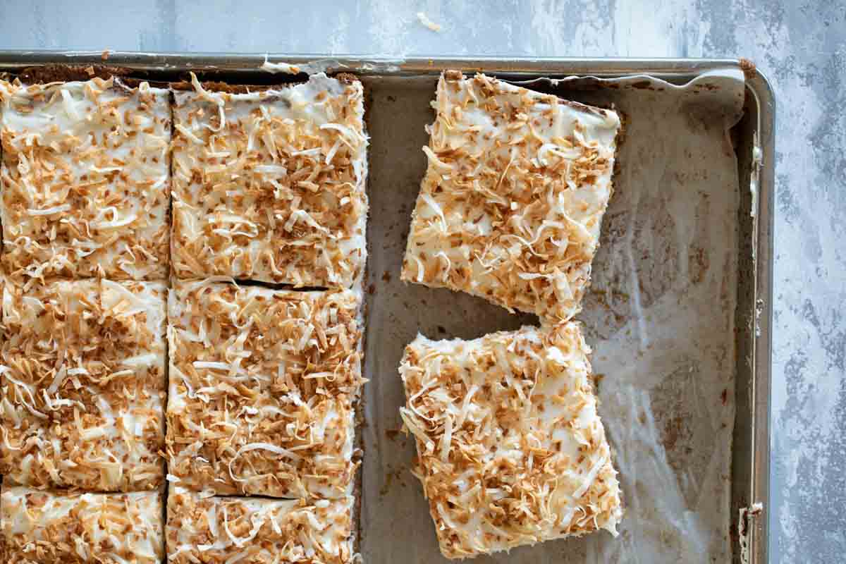 carrot sheet cake cut into pieces in a sheet pan