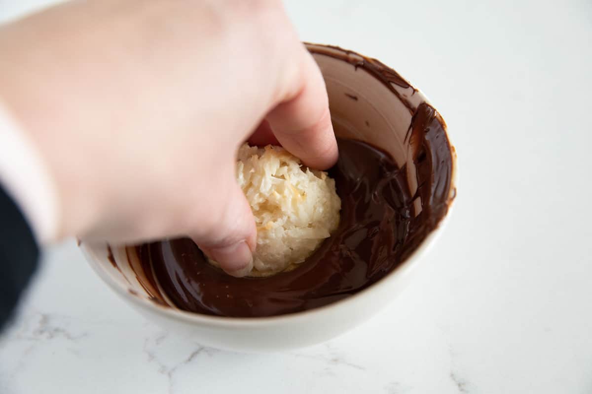 dipping a coconut macaroon in chocolate