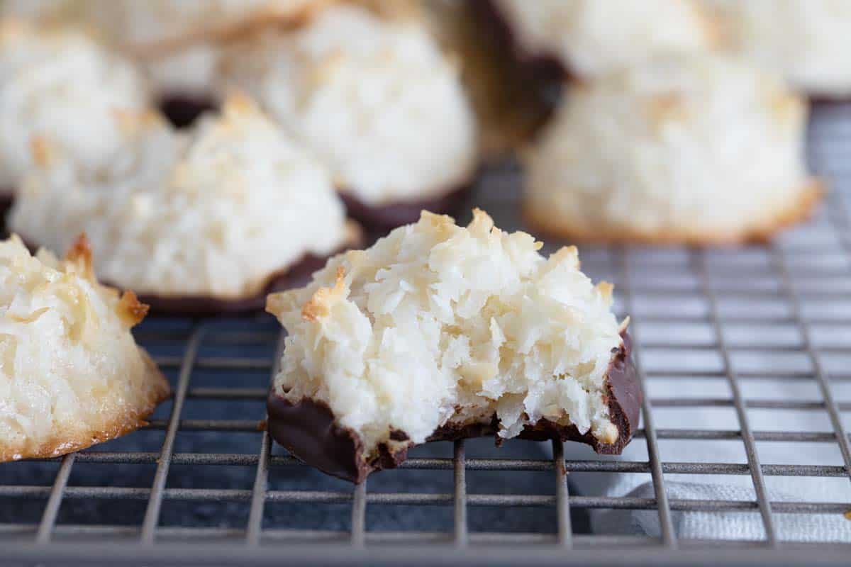 Lightly crispy on the outside and chewy on the inside, these Coconut Macaroons are made for coconut lovers! Dip the bottoms in chocolate for an even more decadent treat. Coconut Macaroon that is dipped in chocolate with a bite taken from it