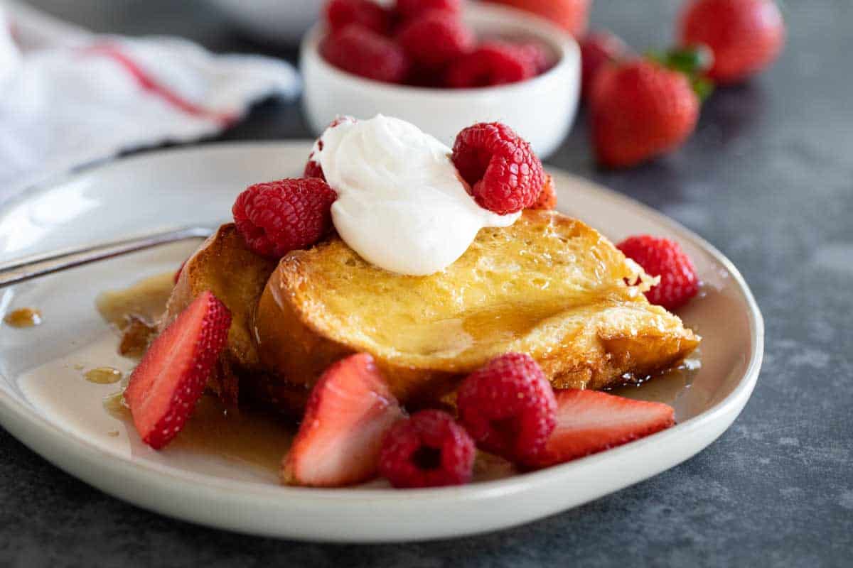 plate with Creme Brulee French Toast topped with berries and whipped cream.