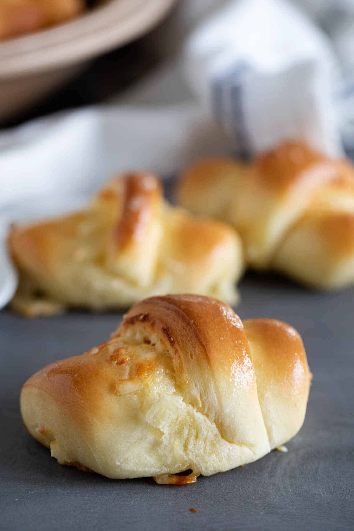 Crescent roll on surface with more behind.