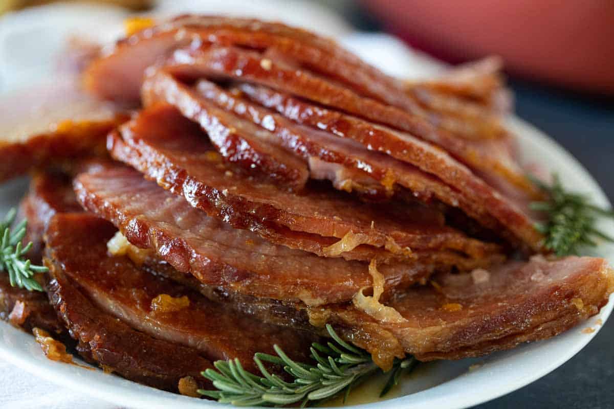 slices of Crock Pot Ham on a plate with fresh rosemary