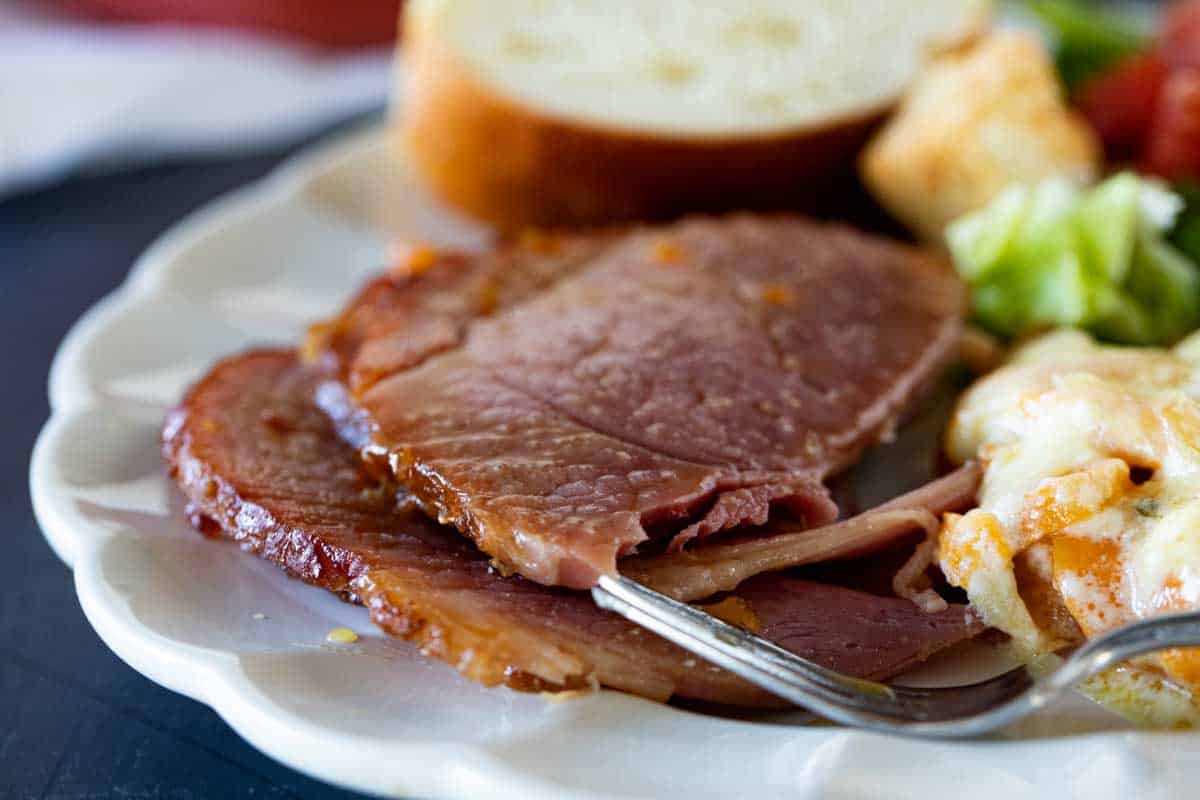 plate with crock pot ham, potatoes, bread and salad