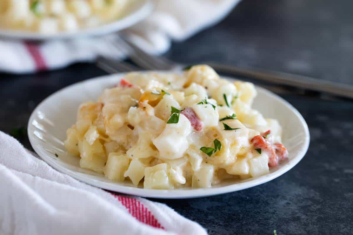 Plate with Crockpot Cheesy Potatoes topped with parsley.