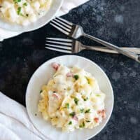 plates with crockpot cheesy potatoes and forks.