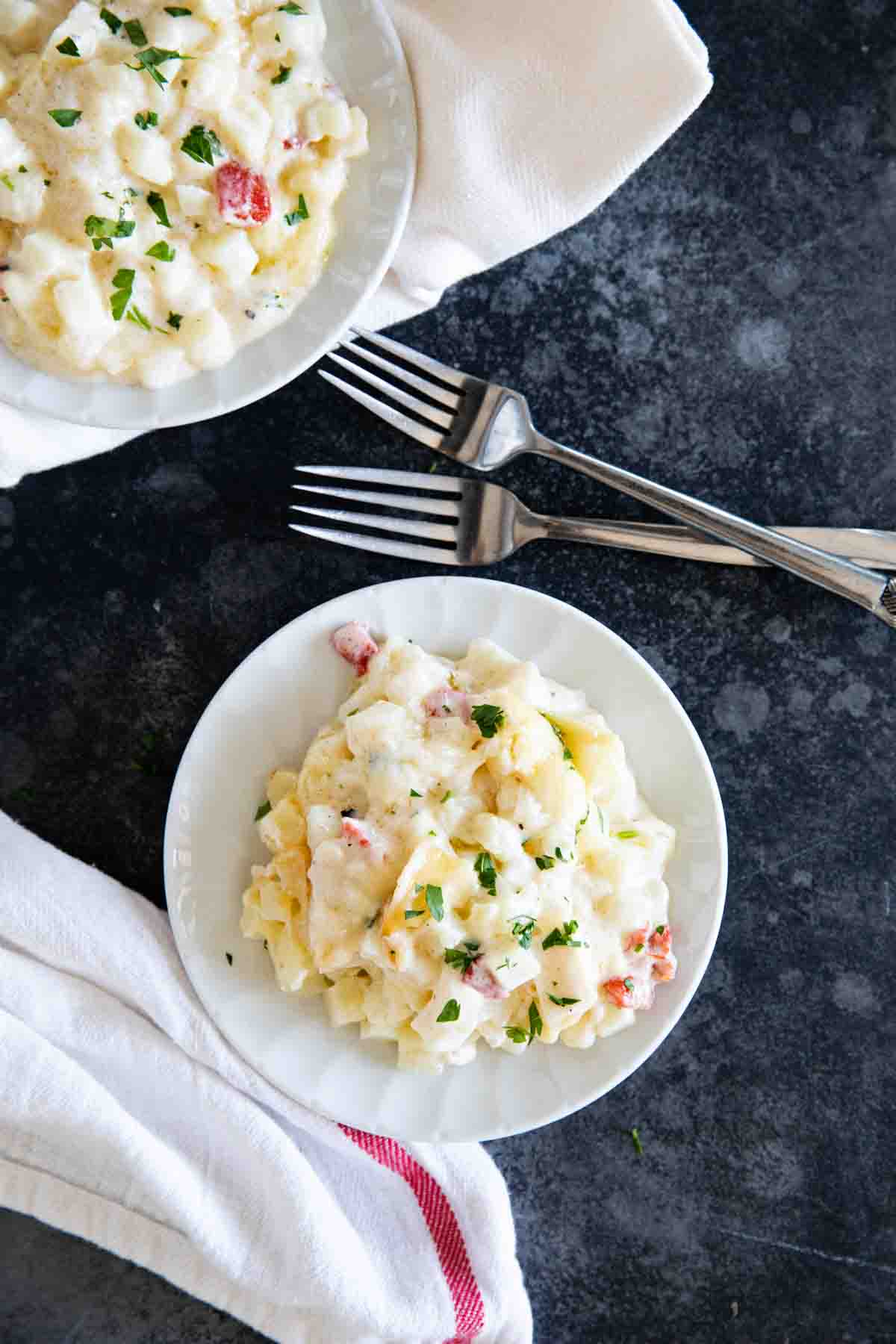 plates with crockpot cheesy potatoes and forks.