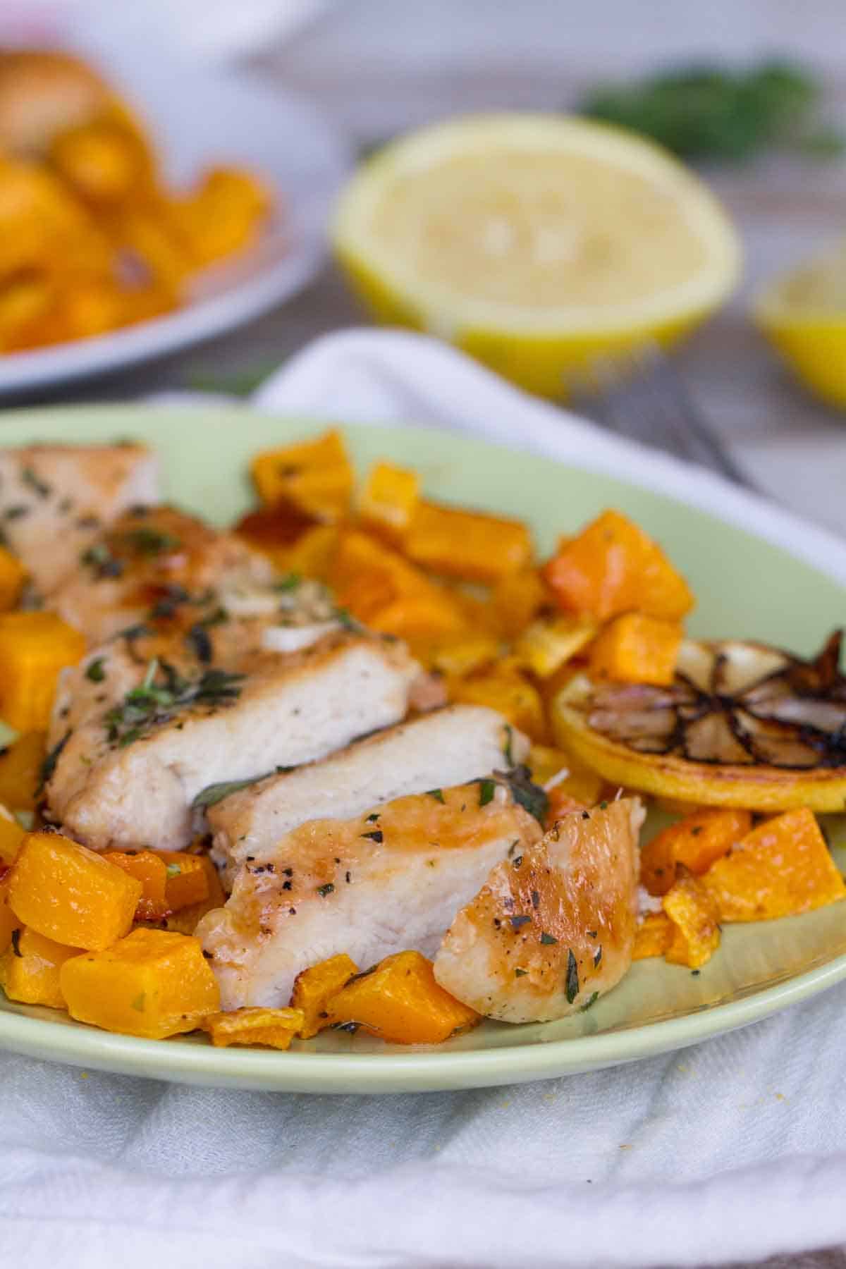 chicken breast sliced with butternut squash and lemons on the plate