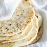 stack of homemade flour tortillas wrapped in a towel.