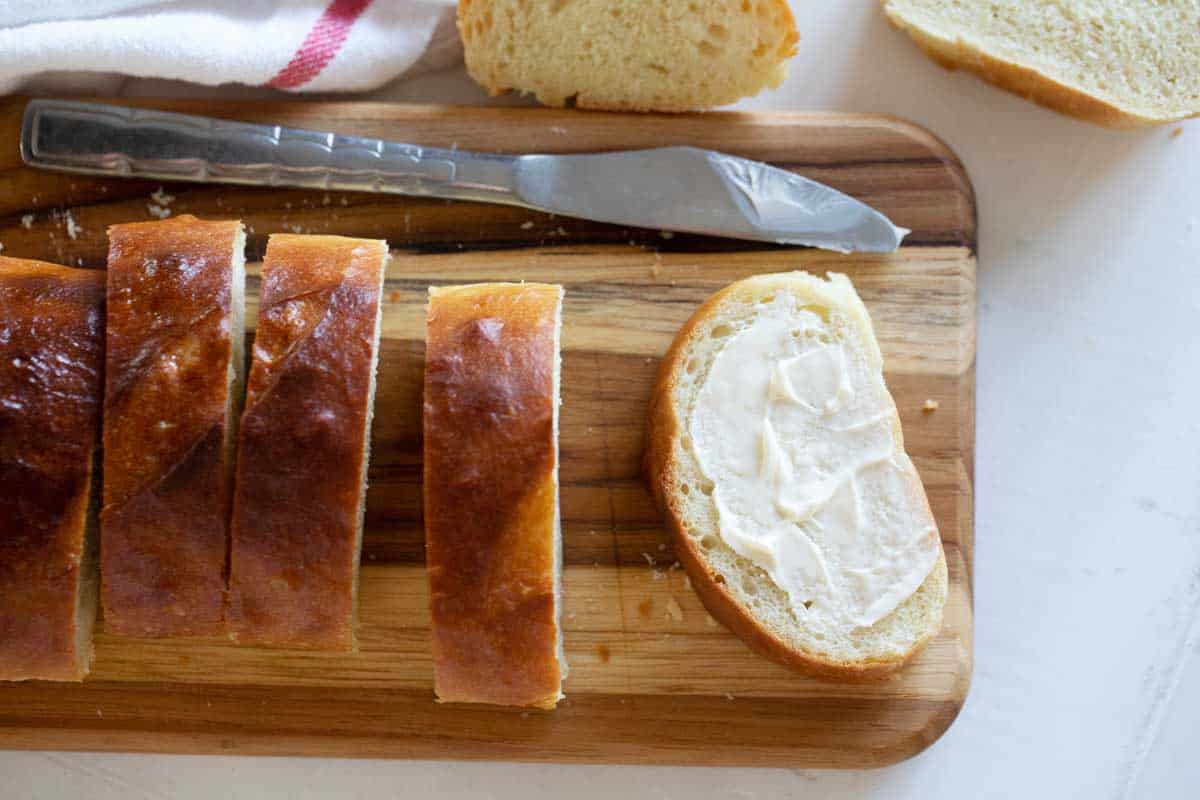 sliced loaf of French Bread with butter on one slice