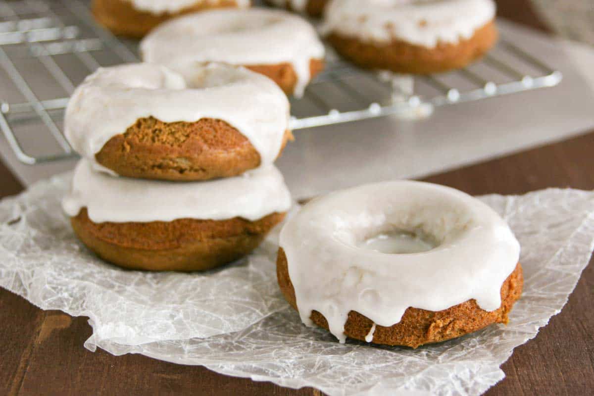Glazed Gingerbread Baked Donuts on parchment with more behind