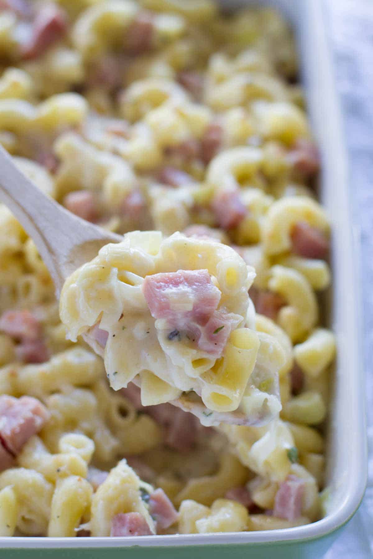 scooping out Mac and Cheese with Ham on a wooden spoon