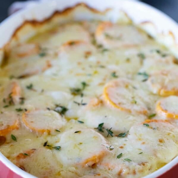 full dish of scalloped sweet potatoes topped with fresh thyme