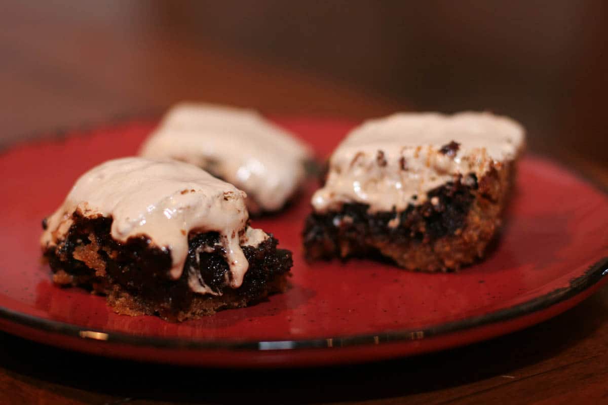 Rich brownies with a graham cracker crust are topped with marshmallows in these S'mores Brownies - a fun twist on s'mores. S'mores Brownies on a red plate