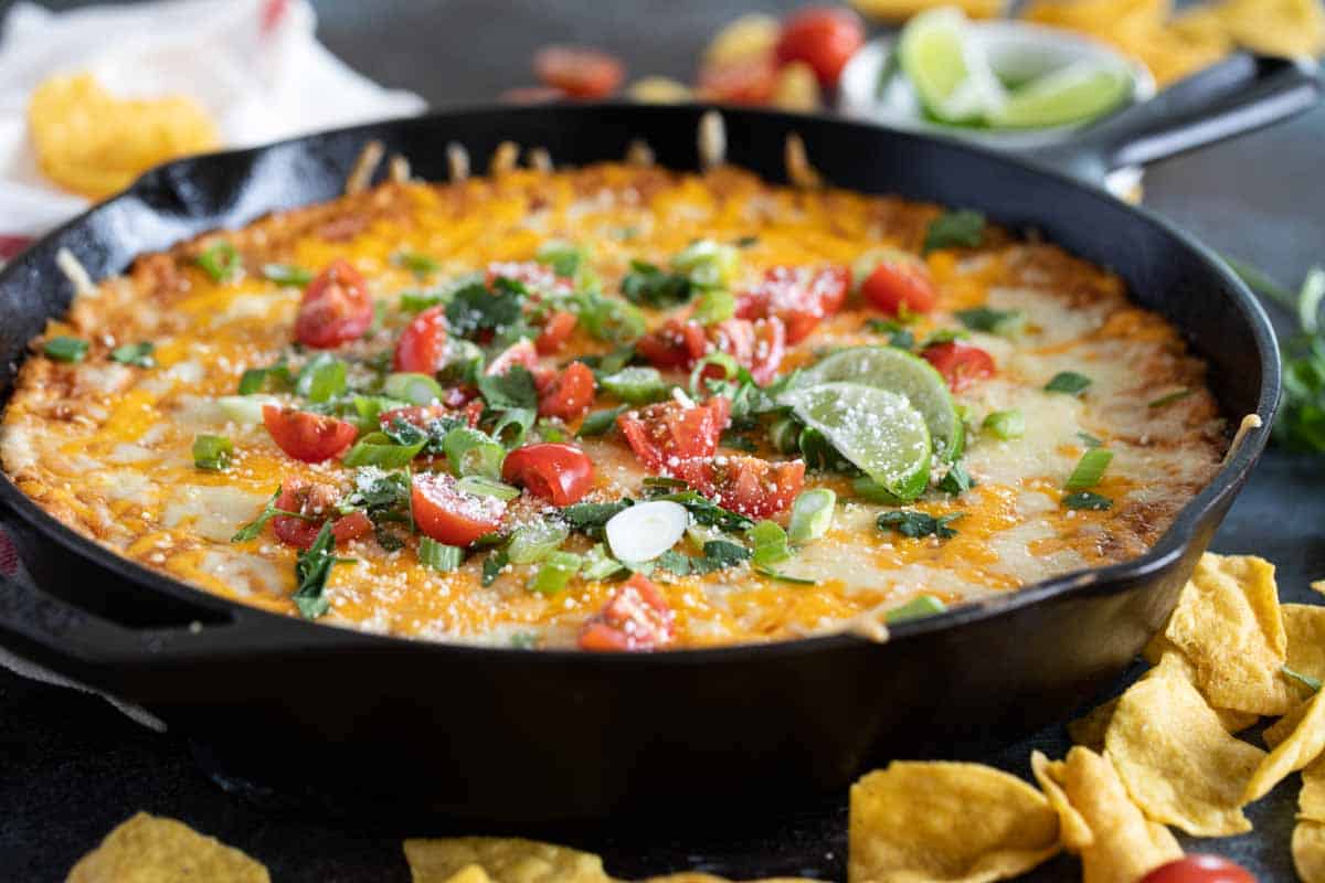 skillet with bean dip topped with cheese and toppings