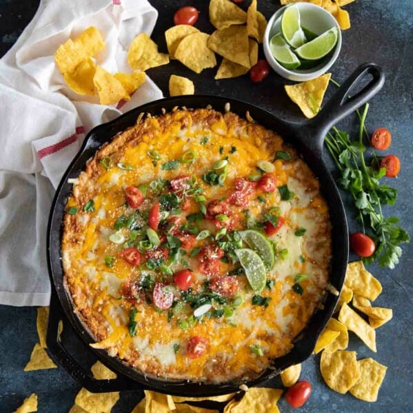 cast iron skillet with bean dip topped with tomatoes and cilantro