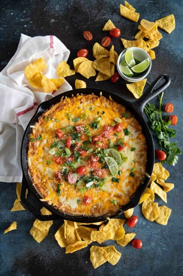 cast iron skillet with bean dip topped with tomatoes and cilantro