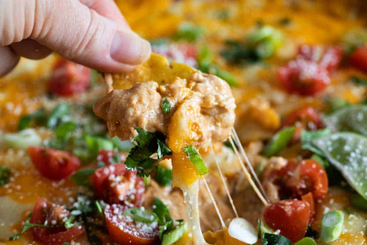 dipping a chip in cheesy bean dip