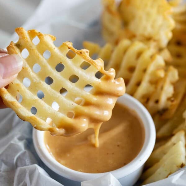 dipping a waffle fry into chick fil a sauce