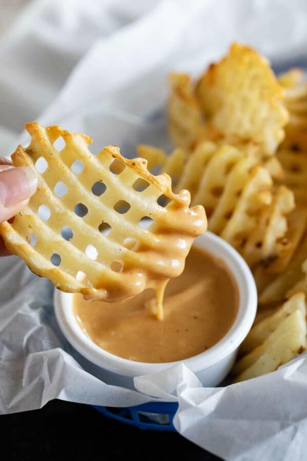 dipping a waffle fry into chick fil a sauce