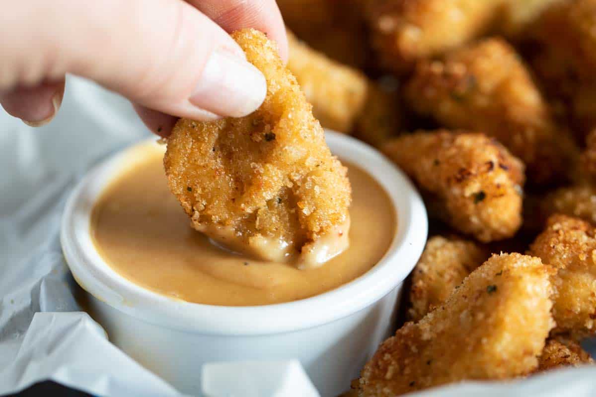 dipping a chicken nugget into chick fil a sauce