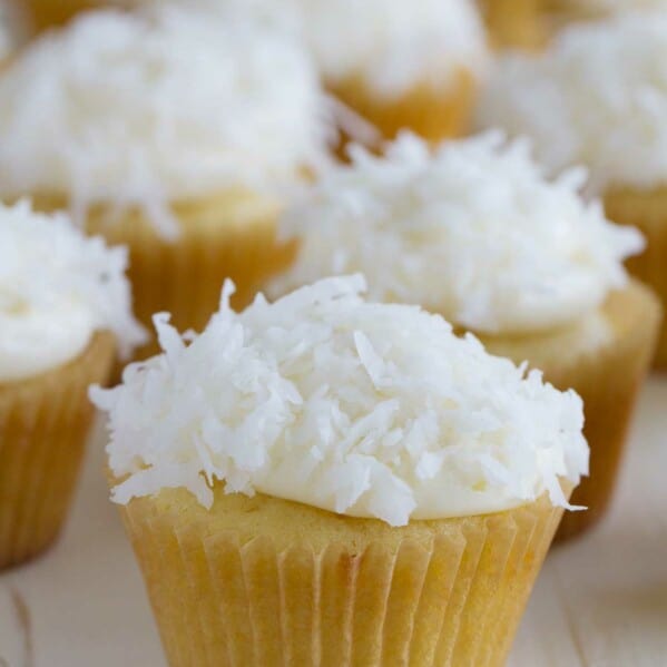 coconut cupcakes topped with cream cheese frosting and coconut