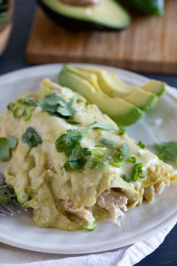 Plate with a serving of Green Chicken Enchiladas topped with cilantro