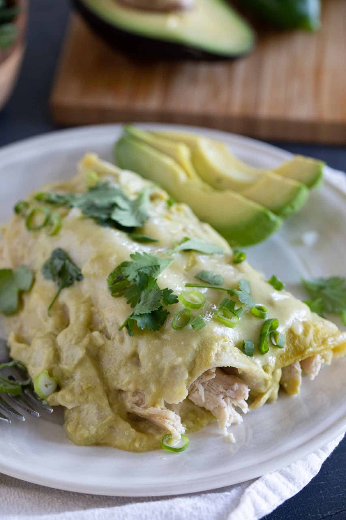 Plate with a serving of Green Chicken Enchiladas topped with cilantro