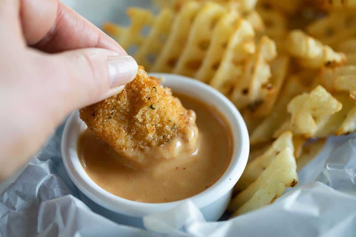dipping a chicken nugget into sauce