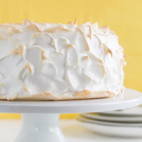 full Lemon Meringue Angel Cake on a cake stand with yellow in the background