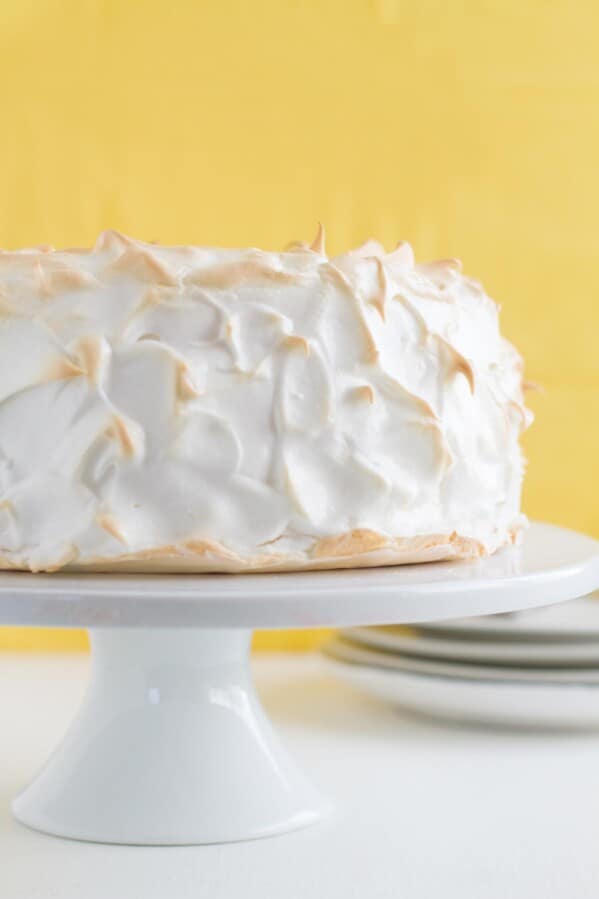 full Lemon Meringue Angel Cake on a cake stand with yellow in the background