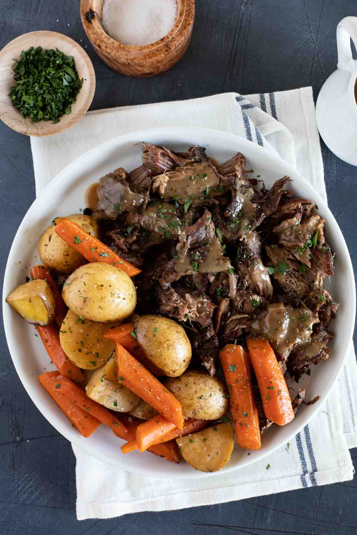 Serving plate with chunks of pot roast with gravy and carrots and potatoes