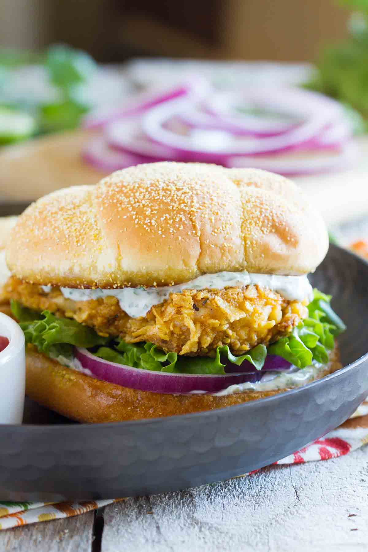 spicy chicken sandwich with cilantro lime mayo, lettuce, and red oimos