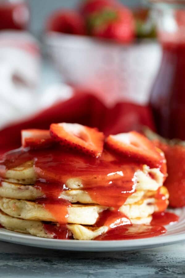stack of Strawberry Pancakes with strawberry syrup and fresh berries