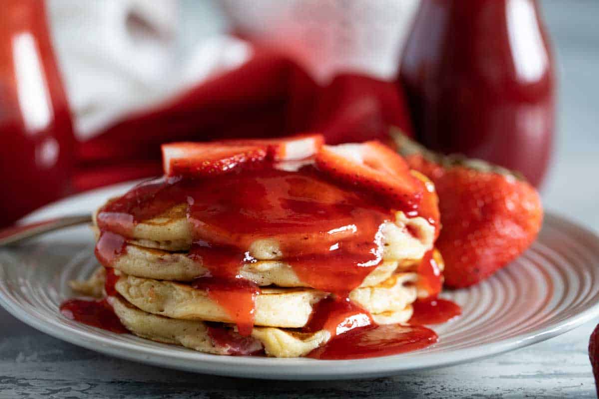 plate of pancakes topped with strawberry syrup