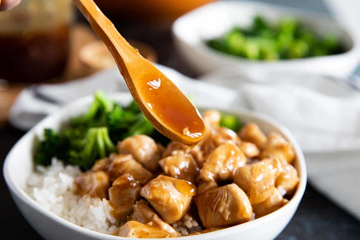 bowl of chicken and rice with teriyaki sauce being spooned over