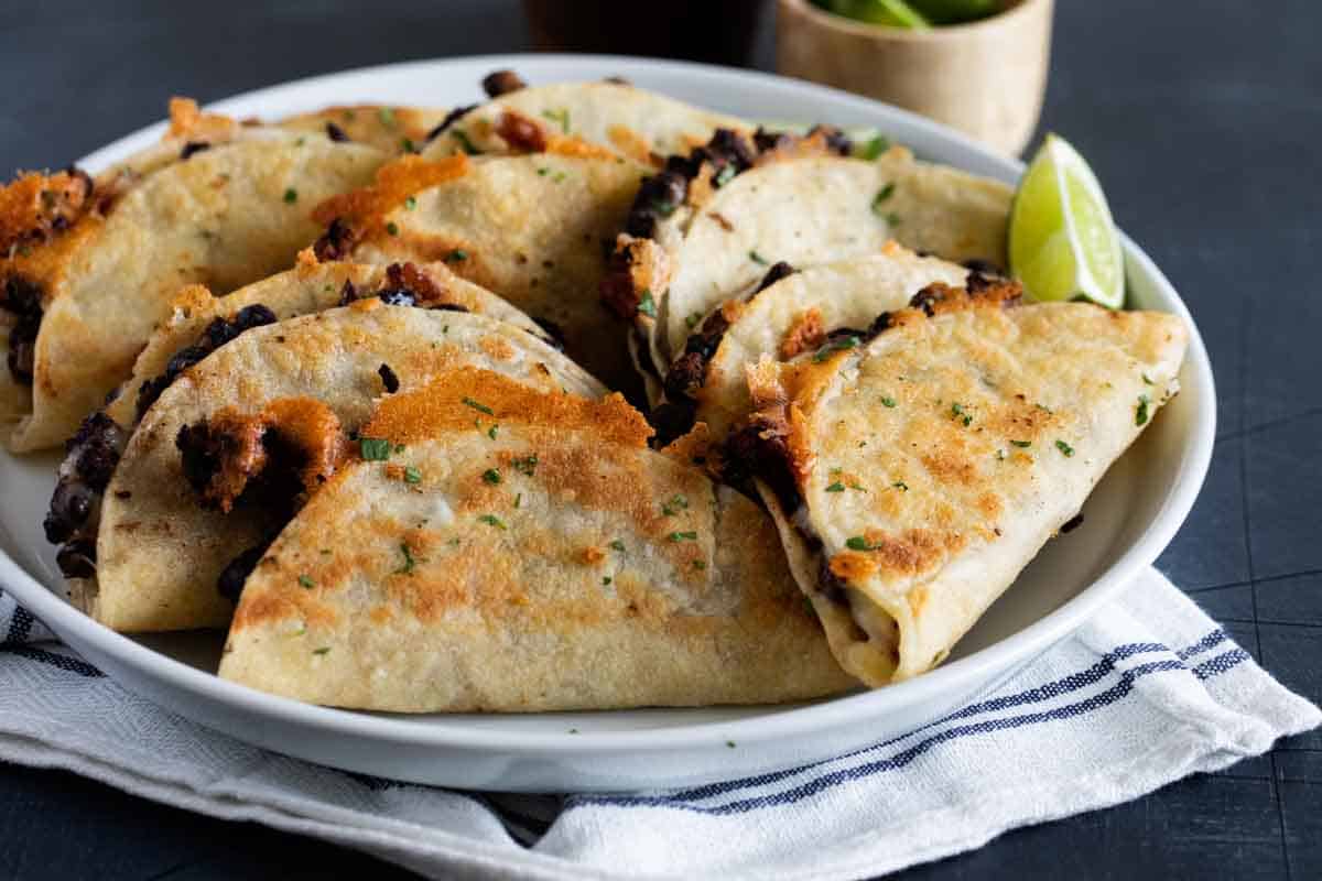 plate full of crispy black bean tacos sprinkled with cilantro