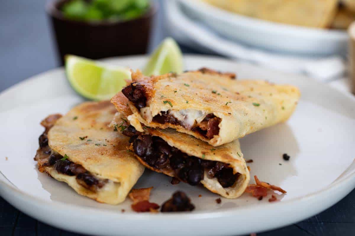 three Black Bean Tacos on a plate with a bite taken from one