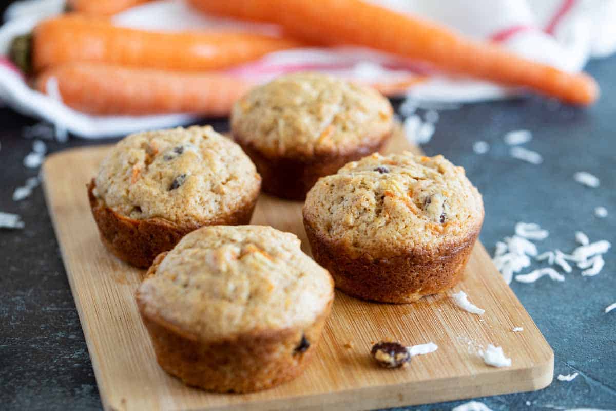 Filled with fresh carrots, coconut, and cinnamon, these Carrot Muffins are so easy and a perfect breakfast muffin. They are tender with just the perfect amount of spice. Carrot muffins on a cutting board