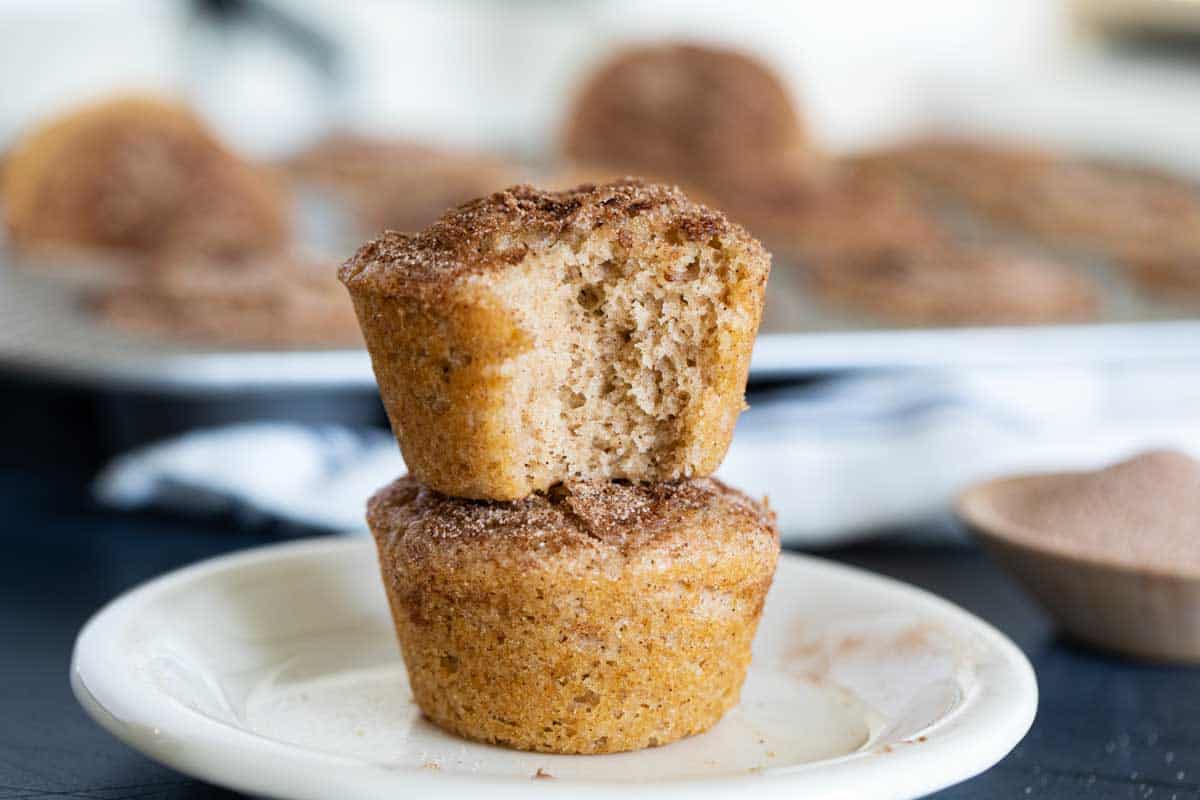 Two Cinnamon Muffins stacked on top of each other with a bite taken from one.