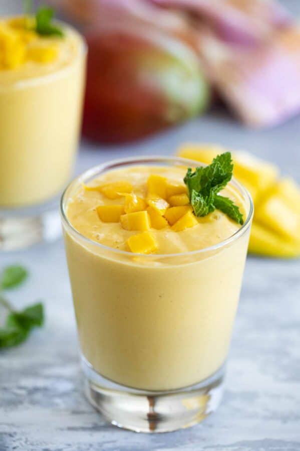 glass of fresh fruit batido topped with fresh mango