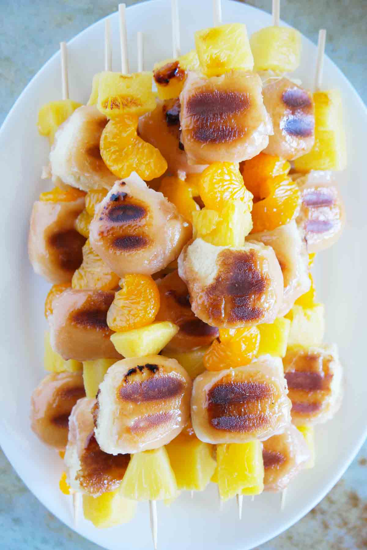 Grilled Donut and Fruit Kabobs stacked on a plate