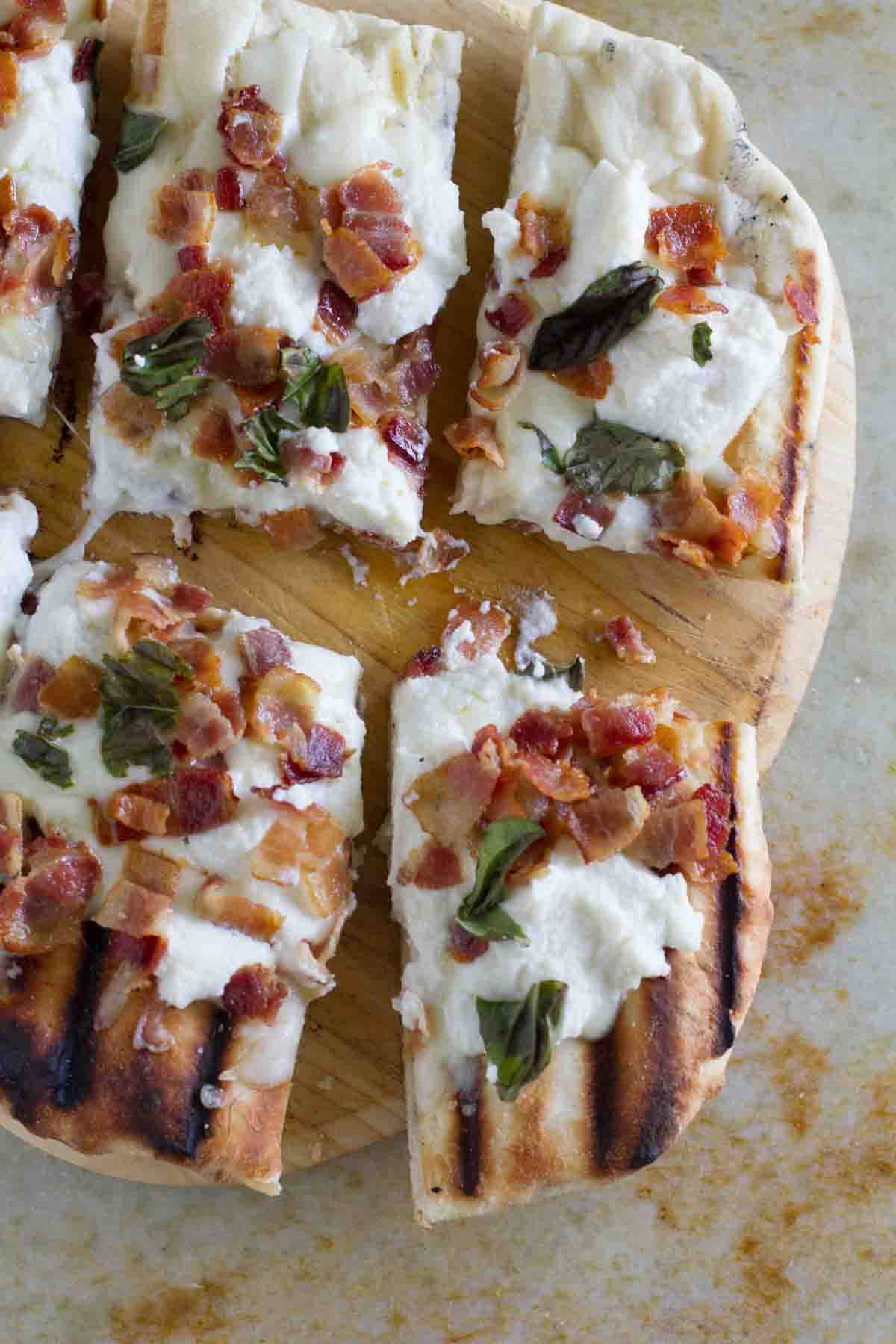 sliced white pizza topped with bacon and basil