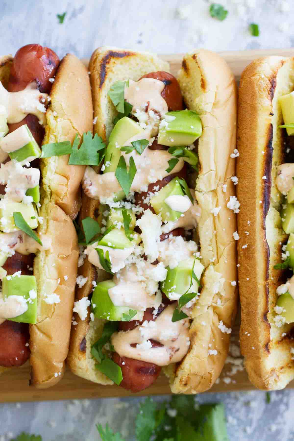 Recipe for Mexican Hot Dogs topped with avocado and cotija