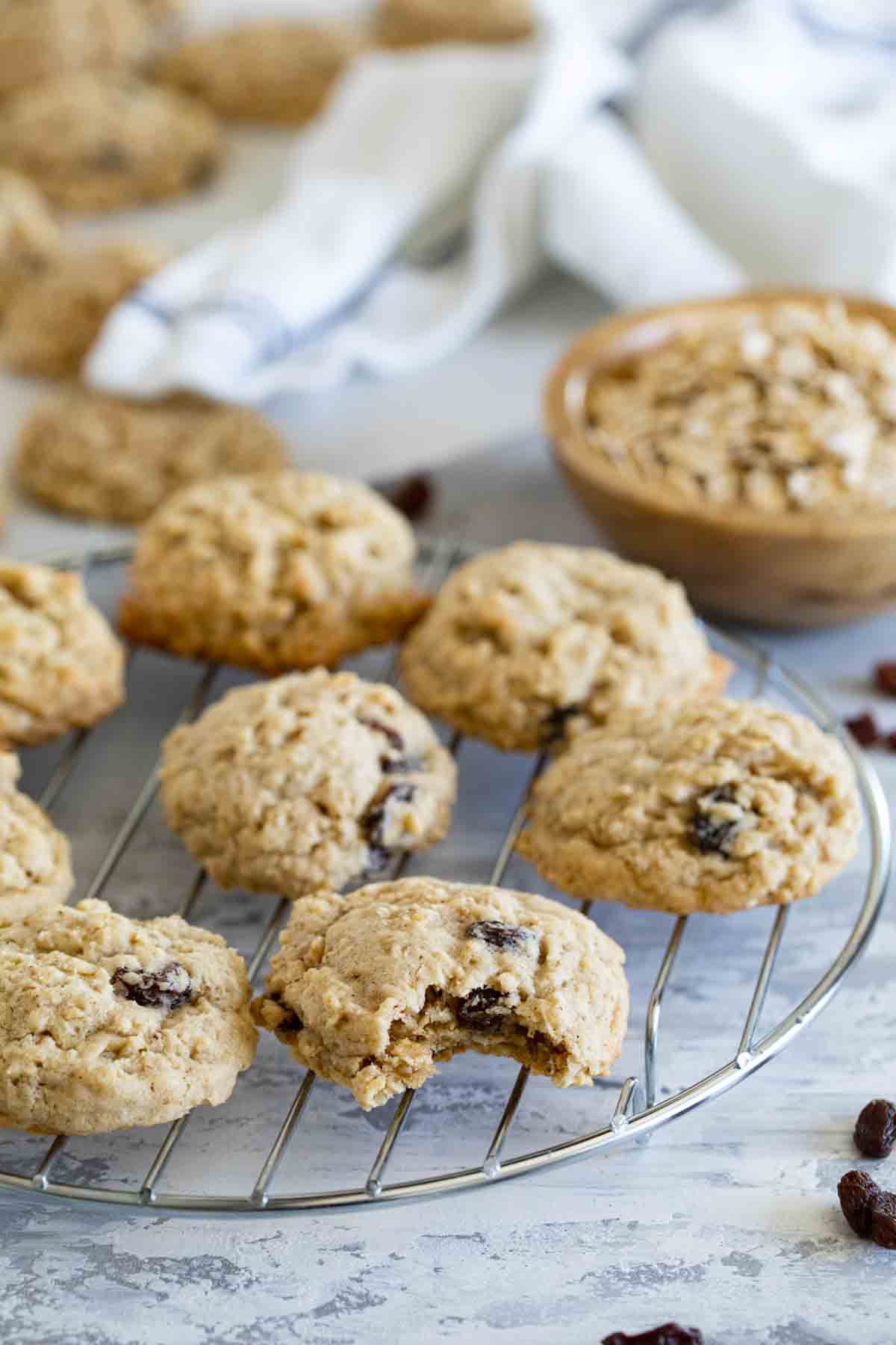 Oatmeal cookies on a cooling rack with a bite taken from one cookie