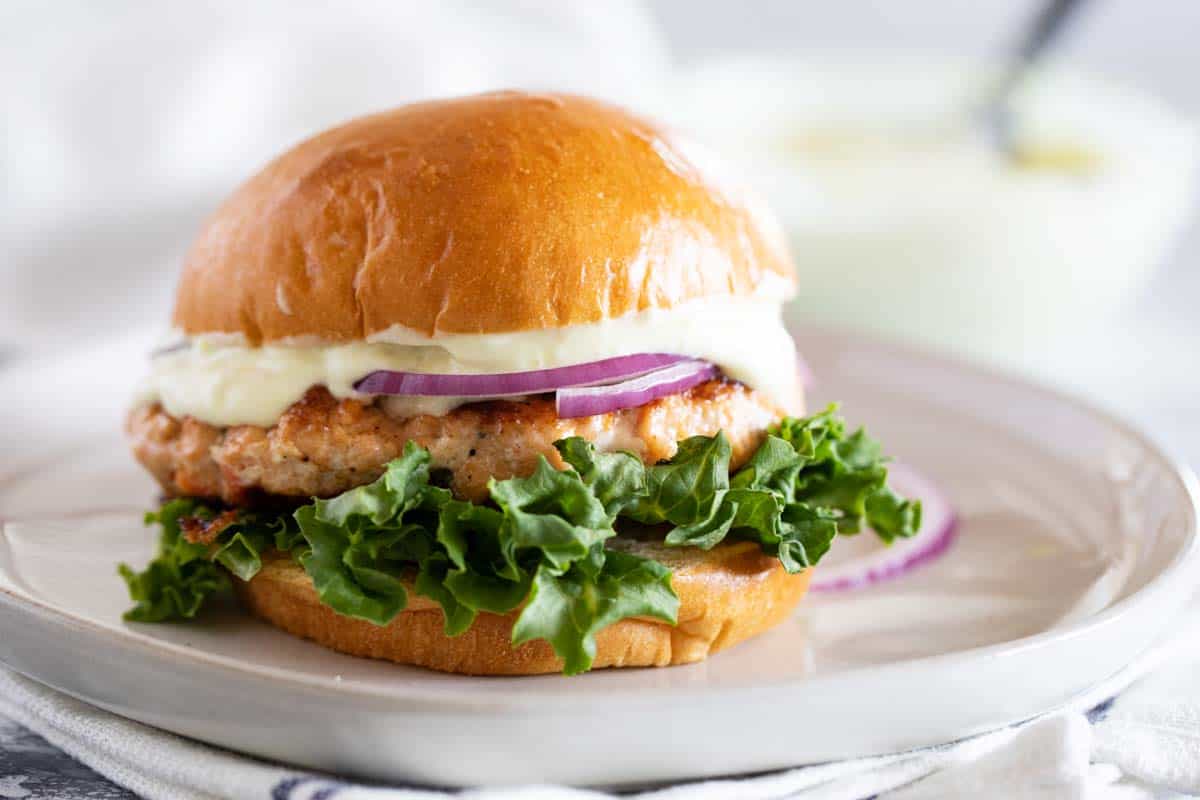 Change up burger night with these Salmon Burgers with Ginger Wasabi Mayonnaise. A delicious dinner with a ton of flavor - perfect for fish lovers! Salmon Burger with ginger wasabi mayo on a plate
