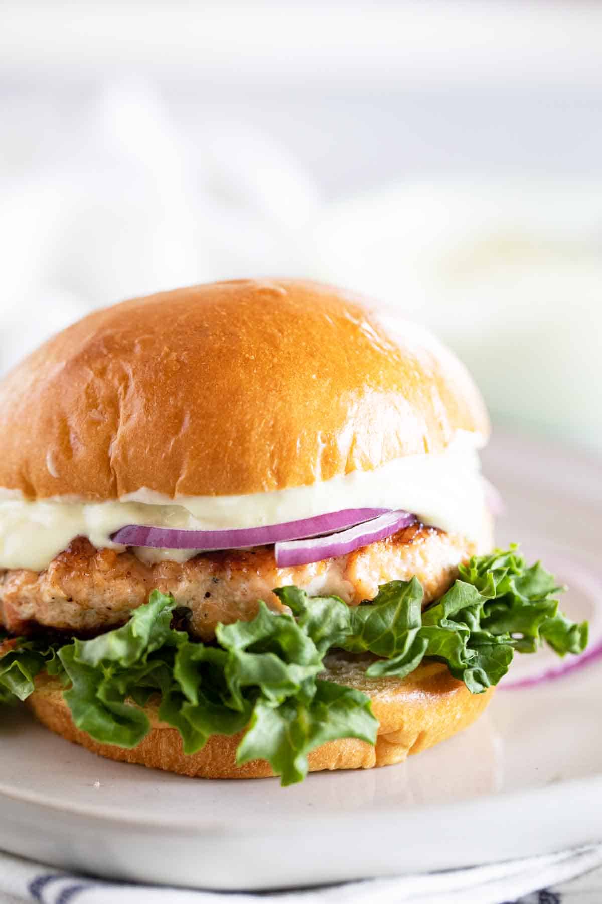 Change up burger night with these Salmon Burgers with Ginger Wasabi Mayonnaise. A delicious dinner with a ton of flavor - perfect for fish lovers! Salmon Burger topped with Ginger Wasabi Mayo with lettuce and onion