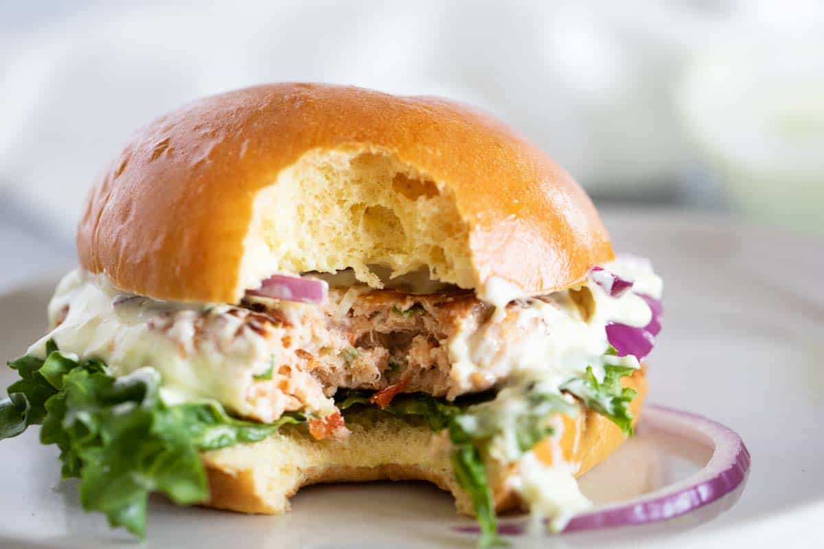 Change up burger night with these Salmon Burgers with Ginger Wasabi Mayonnaise. A delicious dinner with a ton of flavor - perfect for fish lovers! Salmon Burger with a bite taken from it