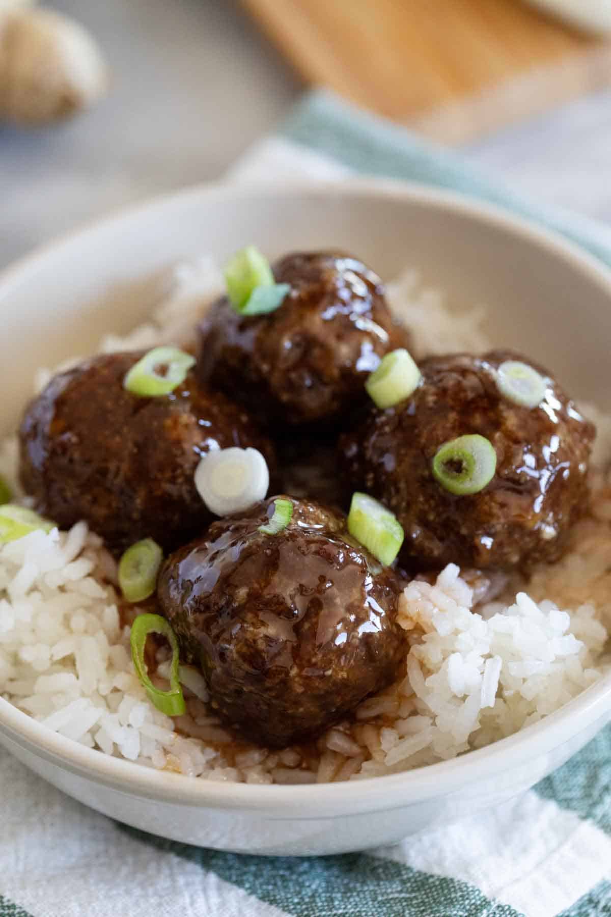 sweet and sour meatballs over rice topped with green onion